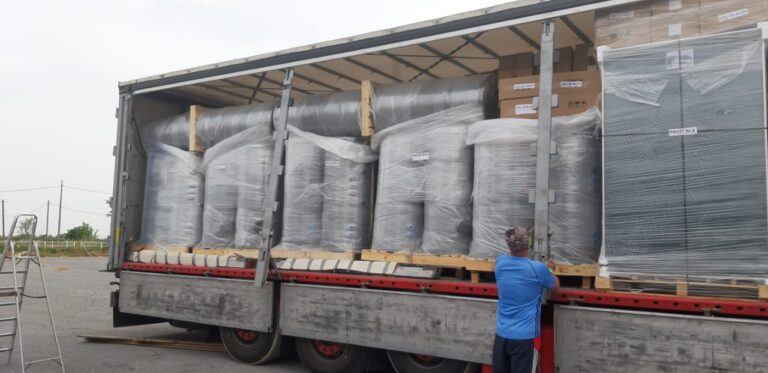 Nákladní auto plné solárních kolektorů a zásobníků vody